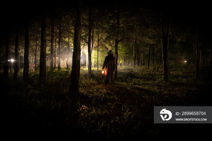 strange light in a dark forest at night. Silhouette of person standing in the dark forest with light