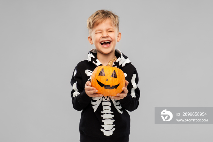 halloween, holiday and childhood concept - happy laughing boy in black costume with skeleton bones h