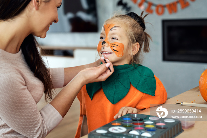 Mom preparing little girl for Halloweens party