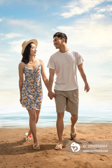 幸福的年轻伴侣在海滩上散步