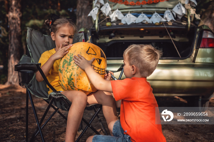 Safe distant Halloween celebration. Kids preparing decoration for party in the trunk of car