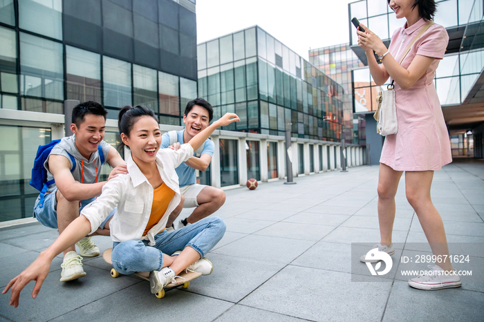 年轻男子向前推着坐在滑板上的女同学