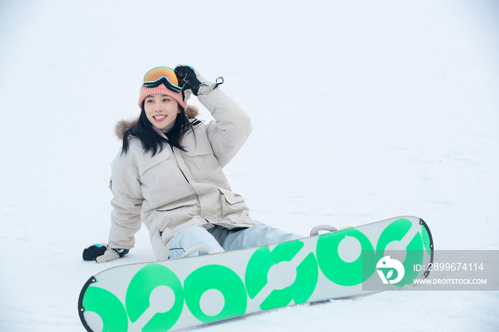 踩着单板坐在雪地上的青年女人