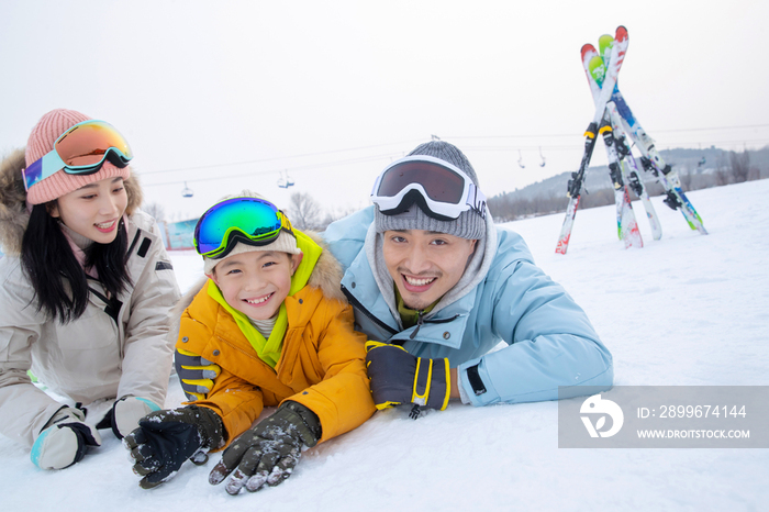 快乐的一家三口趴在雪地上玩耍