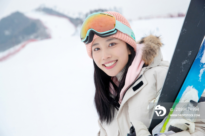 滑雪场上抱着滑雪板漂亮的青年女人