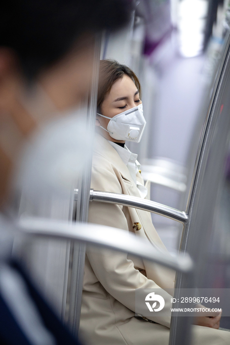 戴口罩的年轻女人在地铁上睡觉