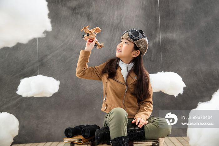 坐在行李箱上的女孩拿着飞机模型