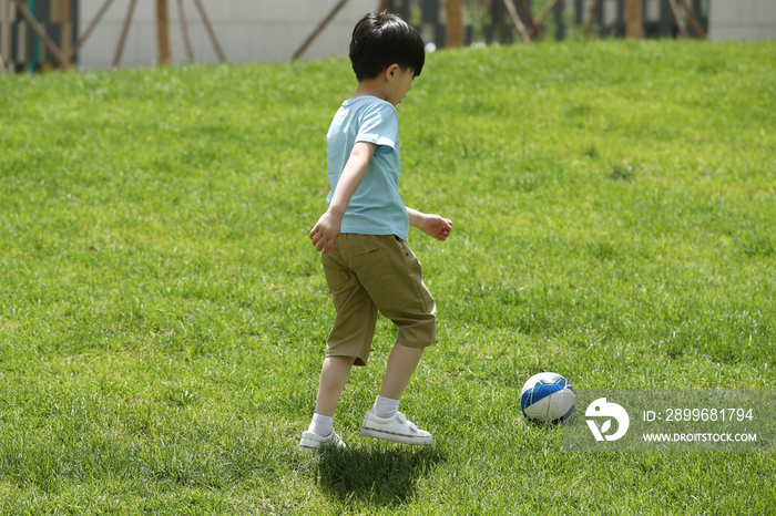 小男孩在草地上踢球