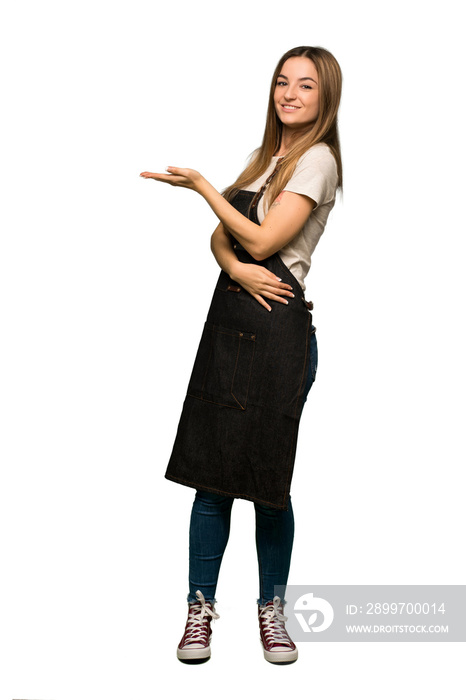 Full body Young woman with apron presenting an idea while looking smiling towards on isolated backgr