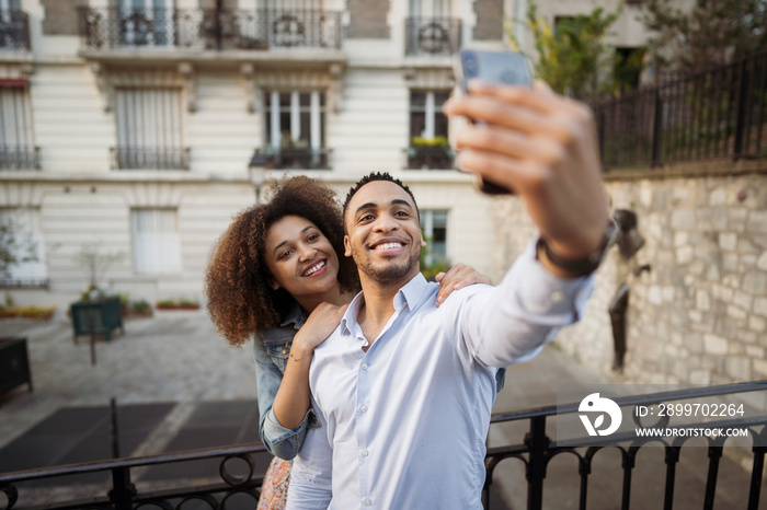 High angle view of happy couple taking selfie with smart phone while standing against building in ci