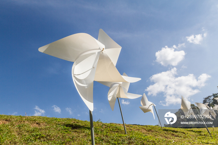 White pinwheel and windmill with blue sky and white cloud background, symbol of happiness