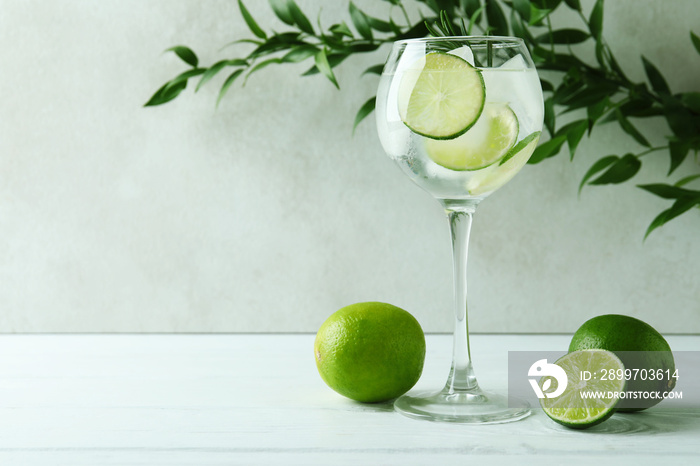 Glass of cocktail with lime on white wooden table