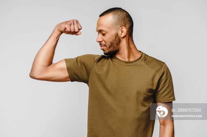 Close up portrait of a happy african american man wearing t-shirt flexing bicep arm muscle