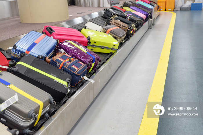 Bright green, pink and blue suitcases on luggage conveyor belt