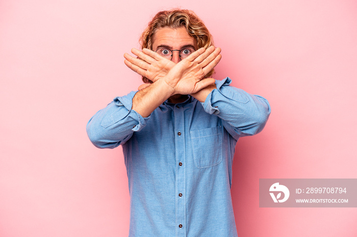 Young caucasian man isolated on pink background doing a denial gesture