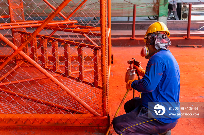 The painter is working to painting the steel structure with spray gun.