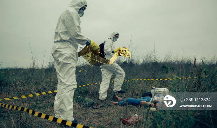 Man and woman in bacteriological protective suits covering a womans body with a thermal blanket