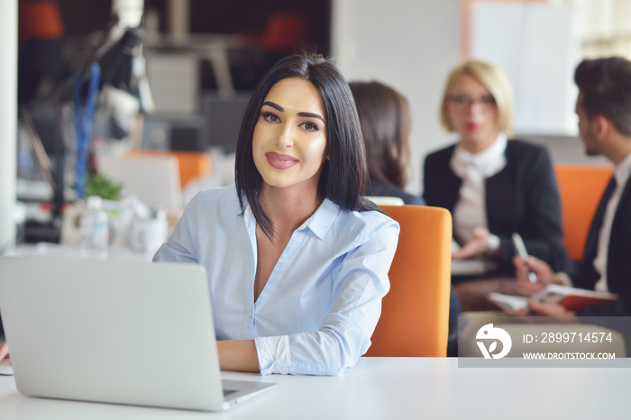 Businesswoman sits at a desk in front of a computer