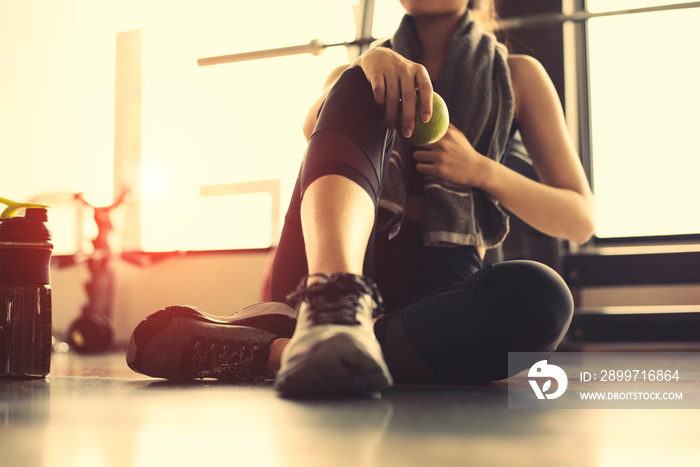 运动女性在健身运动馆锻炼，手里拿着绿苹果。女孩在c刹车后放松