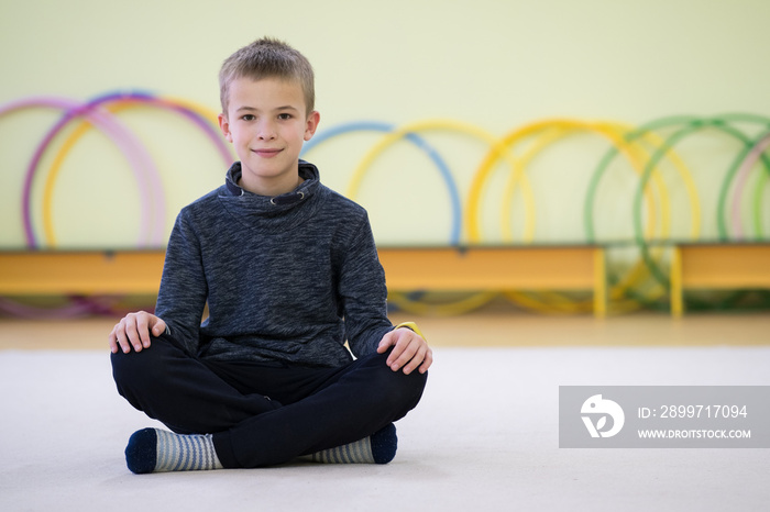 一名幼童在训练后坐在学校运动室内的地板上放松。