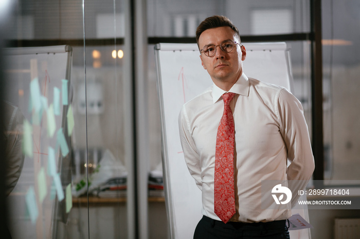 Businessman in conference room use sticky notes on glass wall. Handsome businessman making a busines