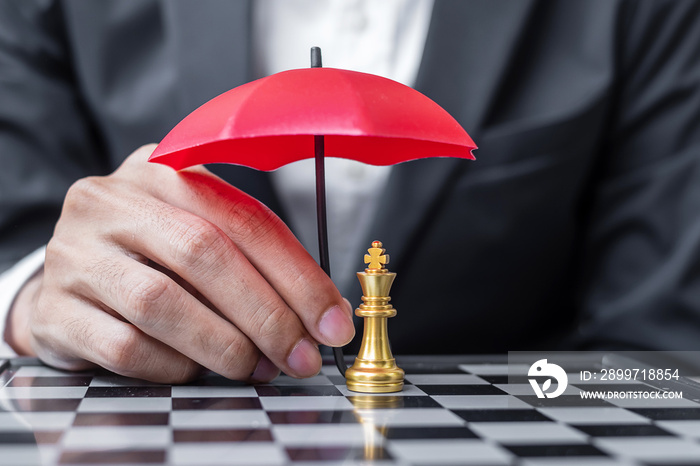 Business man hand holding red Umbrella cover Chess King figure. Business, Risk Management, Solution,