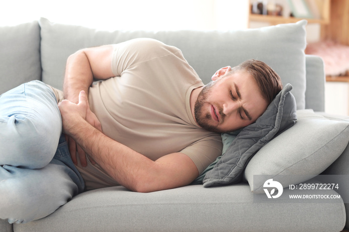 Young man suffering from stomachache at home