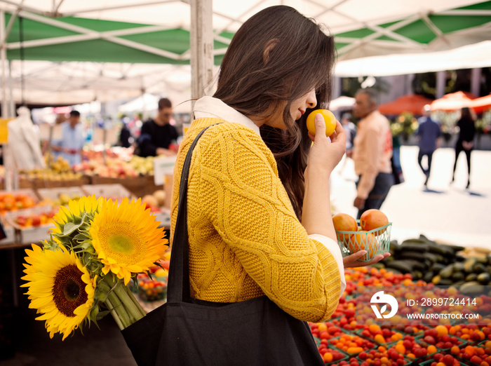 Mid-adult woman carrying sunflowers in her bag