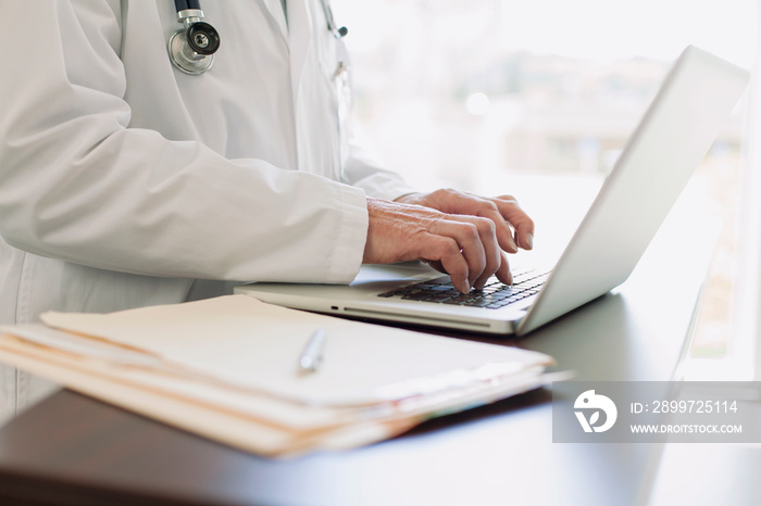 Doctor keyboarding on laptop