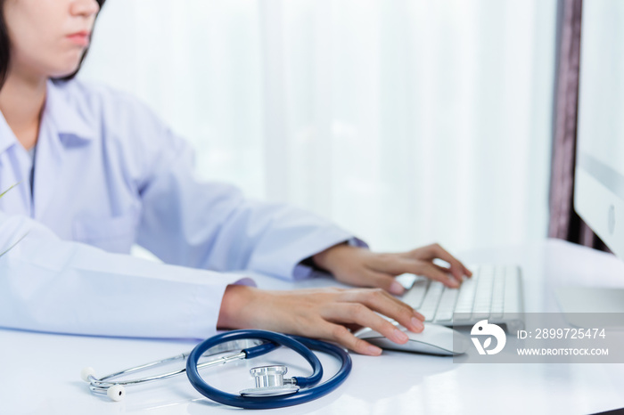 Asian beautiful female doctor smiling wearing doctors uniform with stethoscope typing on keyboard d