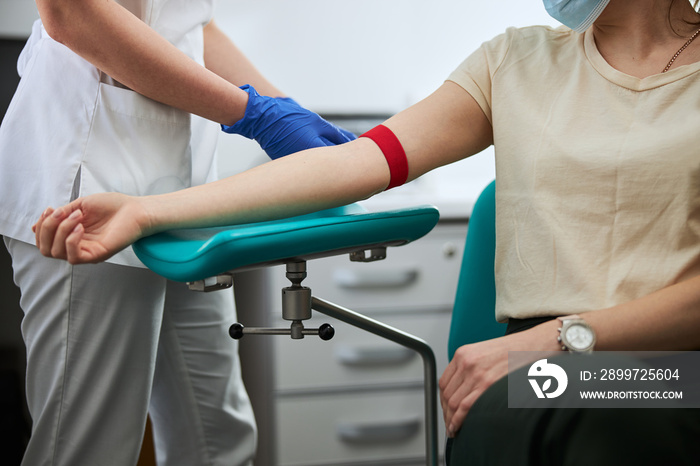 Lab technician placing a tight elastic band around the patient limb