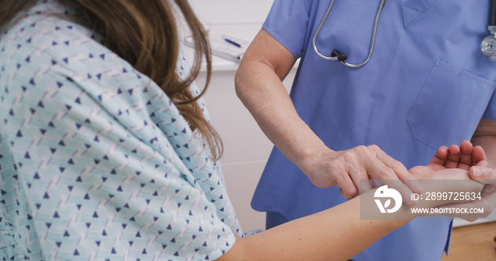医务护士在室内医务室检查年轻患者的脉搏。护士使用fing的近景