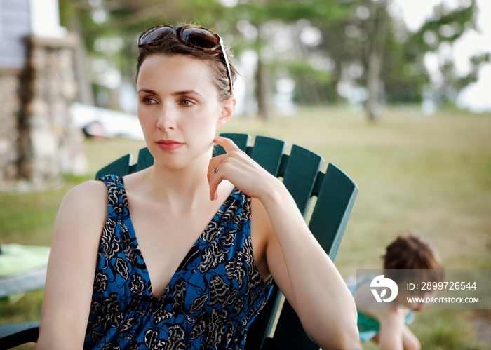 Woman sitting on chair and daughter playing in background