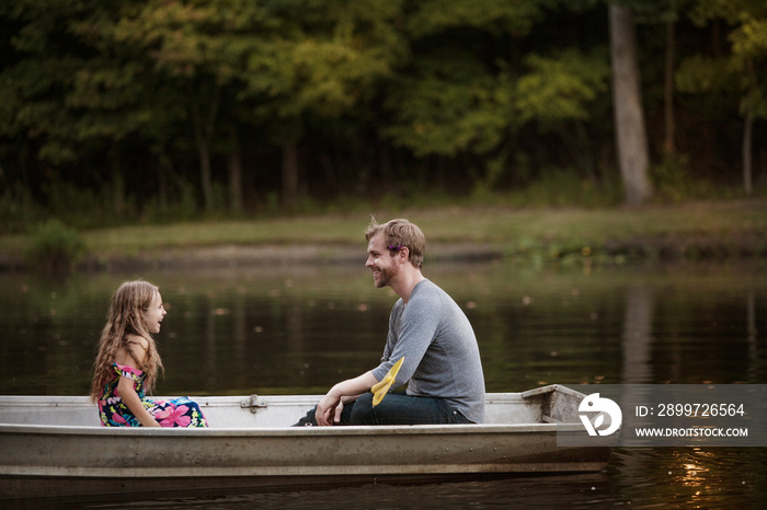 Father and daughter (4-5) face to face on rowboat