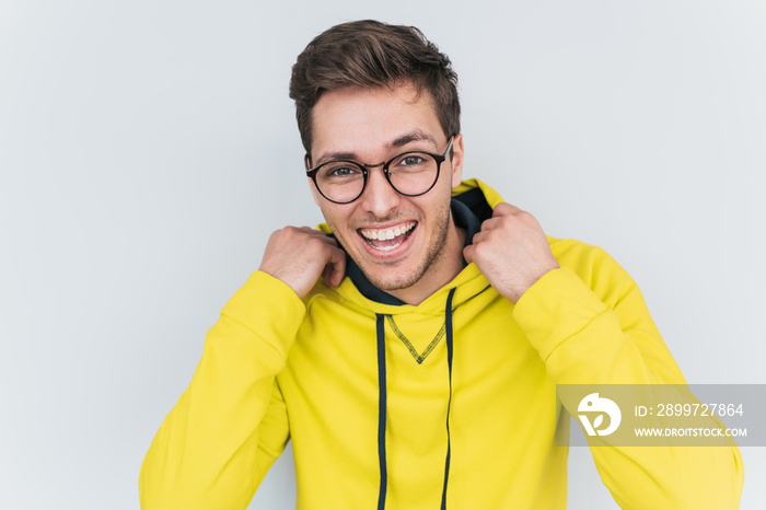 Portrait of happy blond wears yellow hoody and trendy glasses looks cheerful confidently into camera