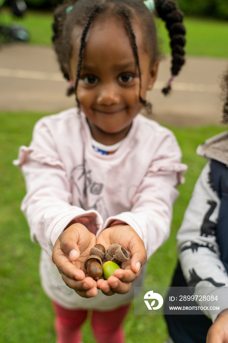 Portrait of smiling girl holding acorns in park in�autumn