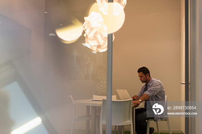 Creative businessman working at laptop in modern conference room