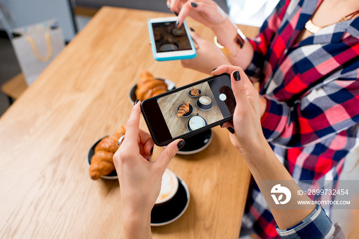 Photographing with smart phone coffee with croissants