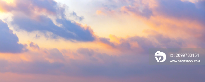 Beautiful cumulus clouds on sunny day at golden hour painted in lavender, purple and pink with sun. 