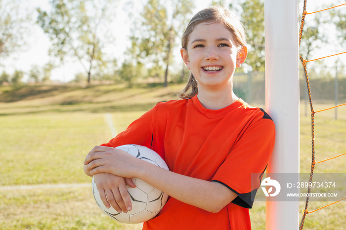 Smiling nine year old female soccer player with soccer ball