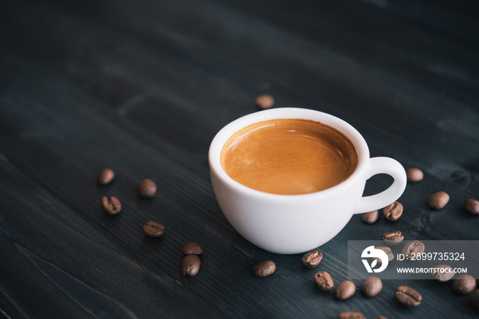 Fresh tasty espresso cup of hot coffee with coffee beans on dark background