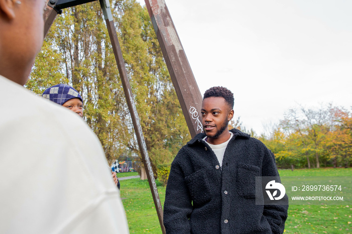 Two black trans masculine friends chatting in the park.