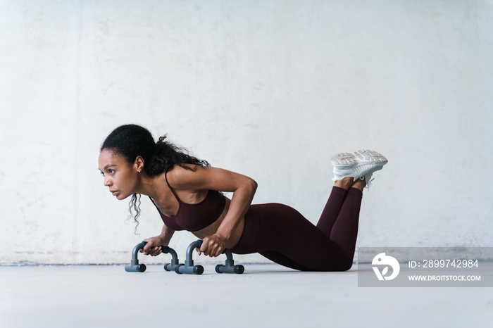 Photo of african american sportswoman working out with push-up stops