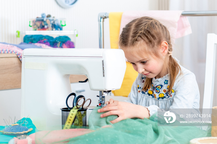 Little girl using sewing machine to make crafts in the workshop