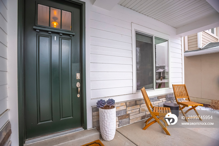 Home facade with glass paned front door and furniture on the concrete porch