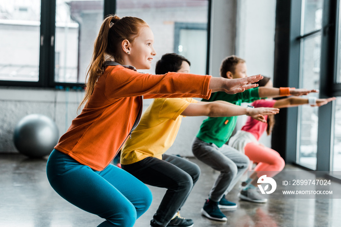 Concentrated kids doing squats during training in gym