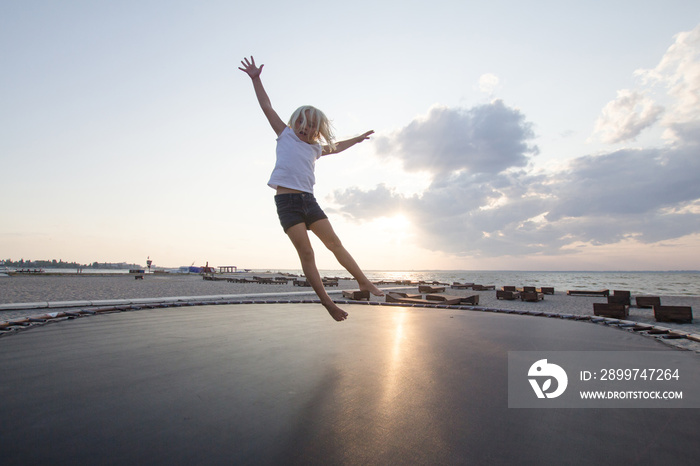 little girl jump and having good time on trampoline in summer time