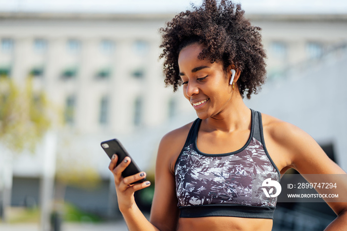 Athletic woman using her mobile phone outdoors.