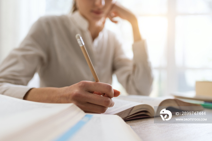 Female student reading a book and doing homework