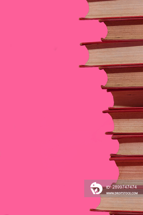 Stacked old books on a pink background.